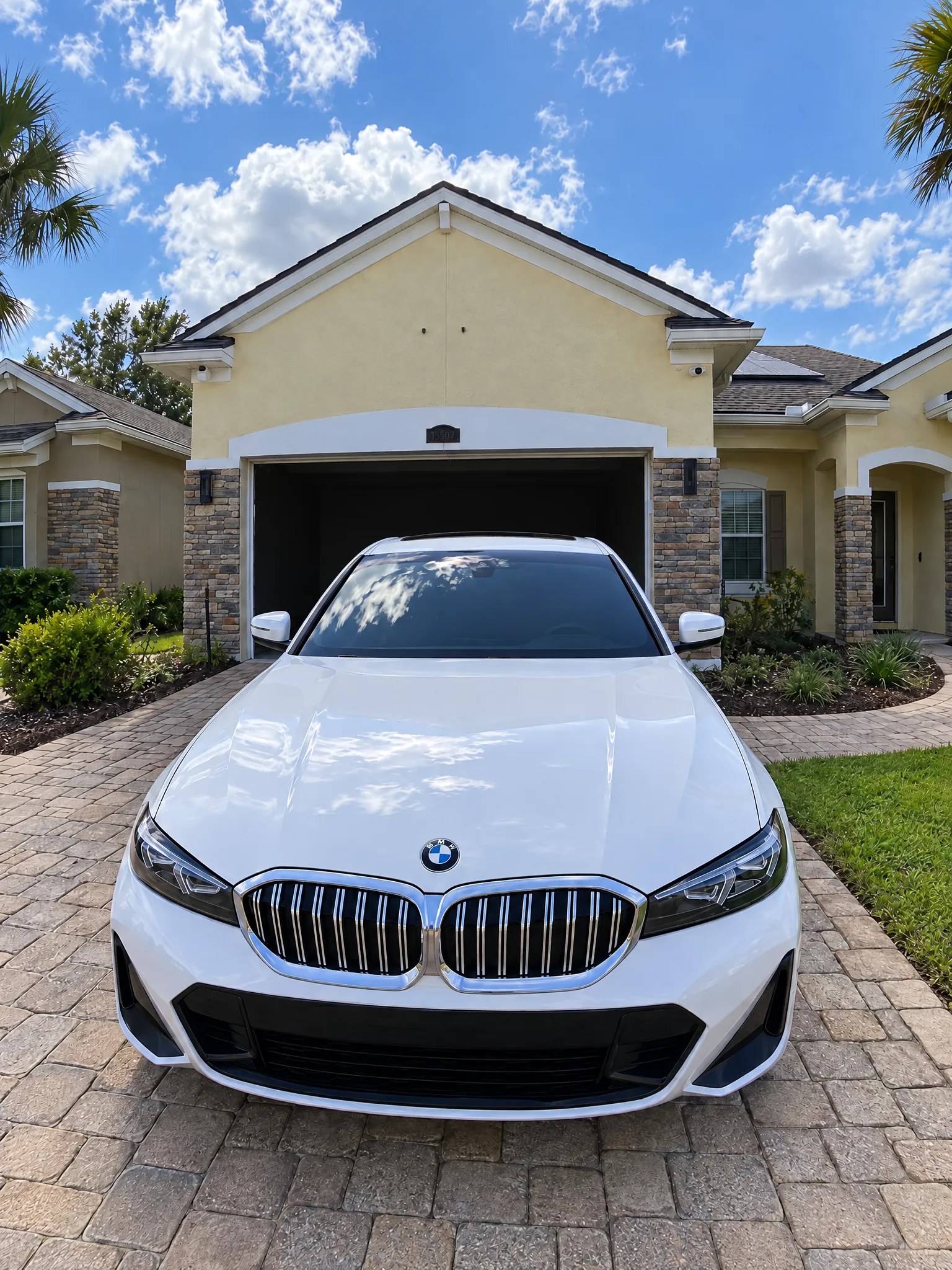 White BMW 3 Series with freshly tinted windows, parked on a paver driveway in Jacksonville