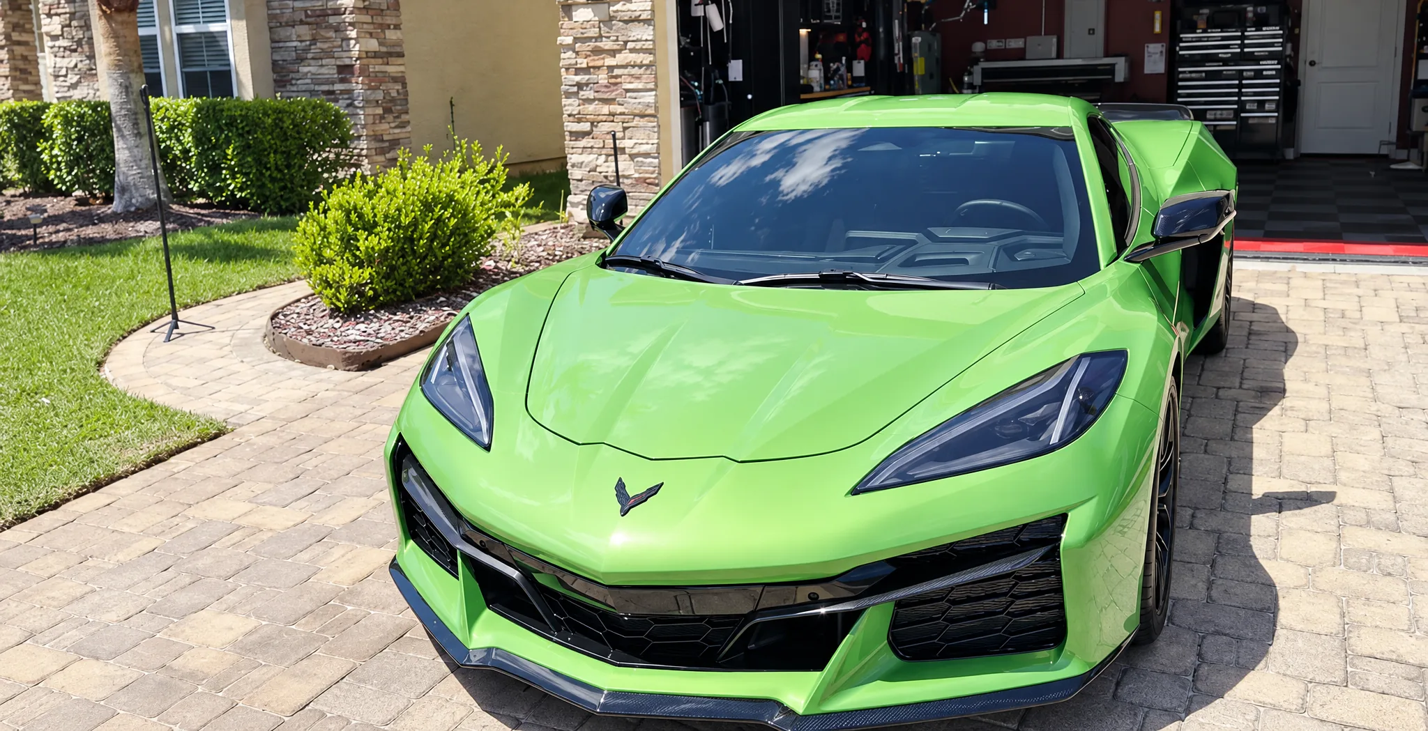 Green Chevrolet Corvette Z06 with tinted windows, parked on a paver driveway